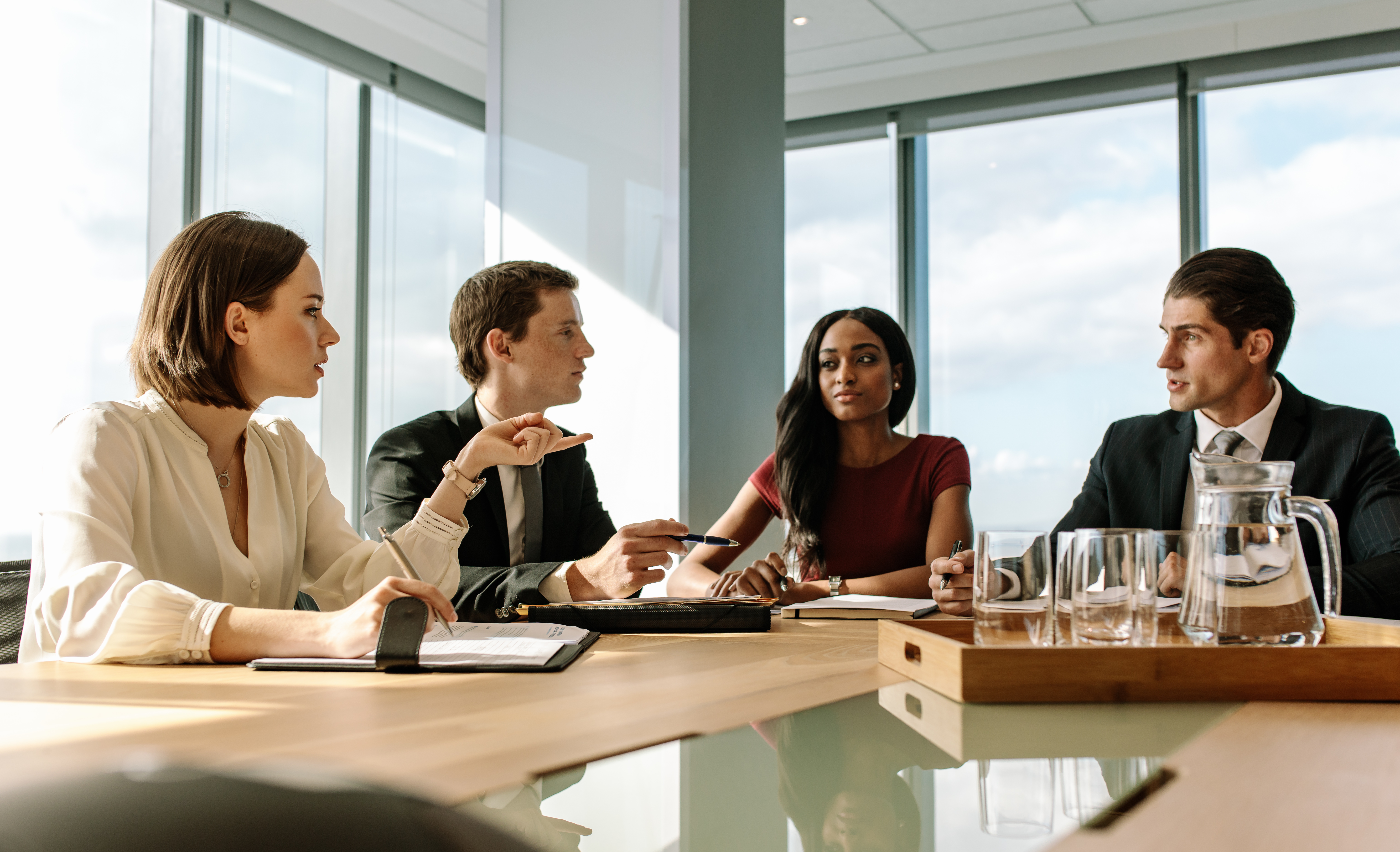 2 homens e 2 mulheres sentados em uma mesa de reunião conversando